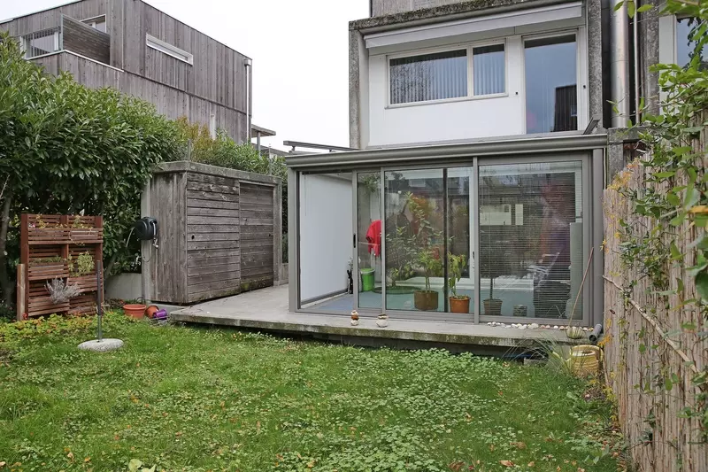 vue large d'un jardin avec pelouse et veranda grise